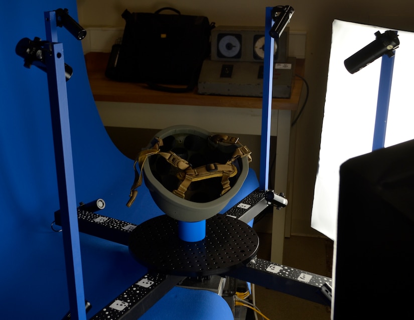 A military helmet sits upside down on a circular metal plate for photo scanning purposes.