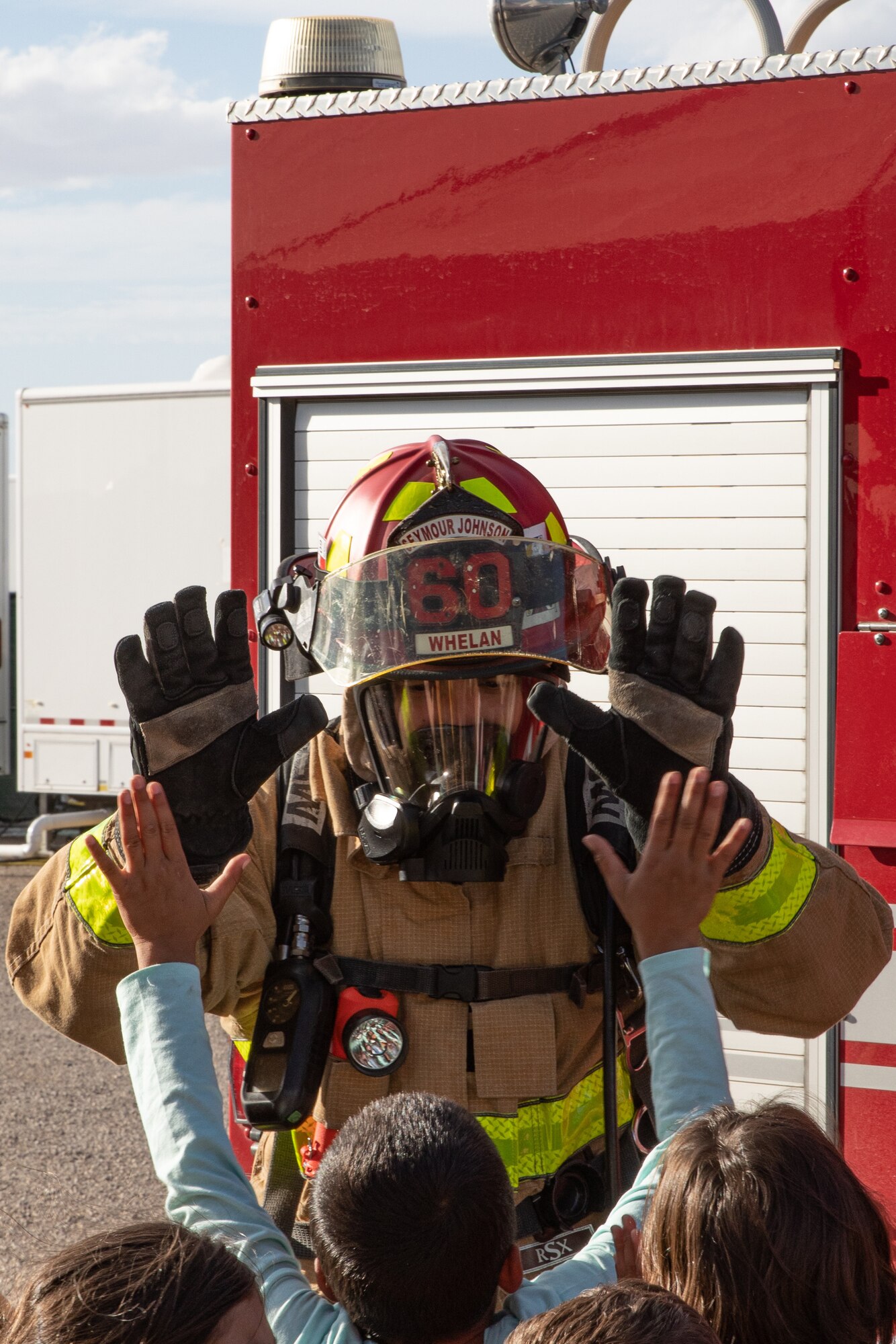 Tech. Sgt. Matt Whelan, Task Force-Holloman firefighter deployed from Seymour Johnson Air Force Base, North Carolina, gives a high five to an Afghan child during a fire safety class on Holloman Air Force Base, New Mexico, Oct. 11, 2021. The Department of Defense, through the U.S. Northern Command, and in support of the Department of State and Department of Homeland Security, is providing transportation, temporary housing, medical screening, and general support for at least 50,000 Afghan evacuees at suitable facilities, in permanent or temporary structures, as quickly as possible. This initiative provides Afghan evacuees essential support at secure locations outside Afghanistan. (U.S. Army photo by Spc. Nicholas Goodman)