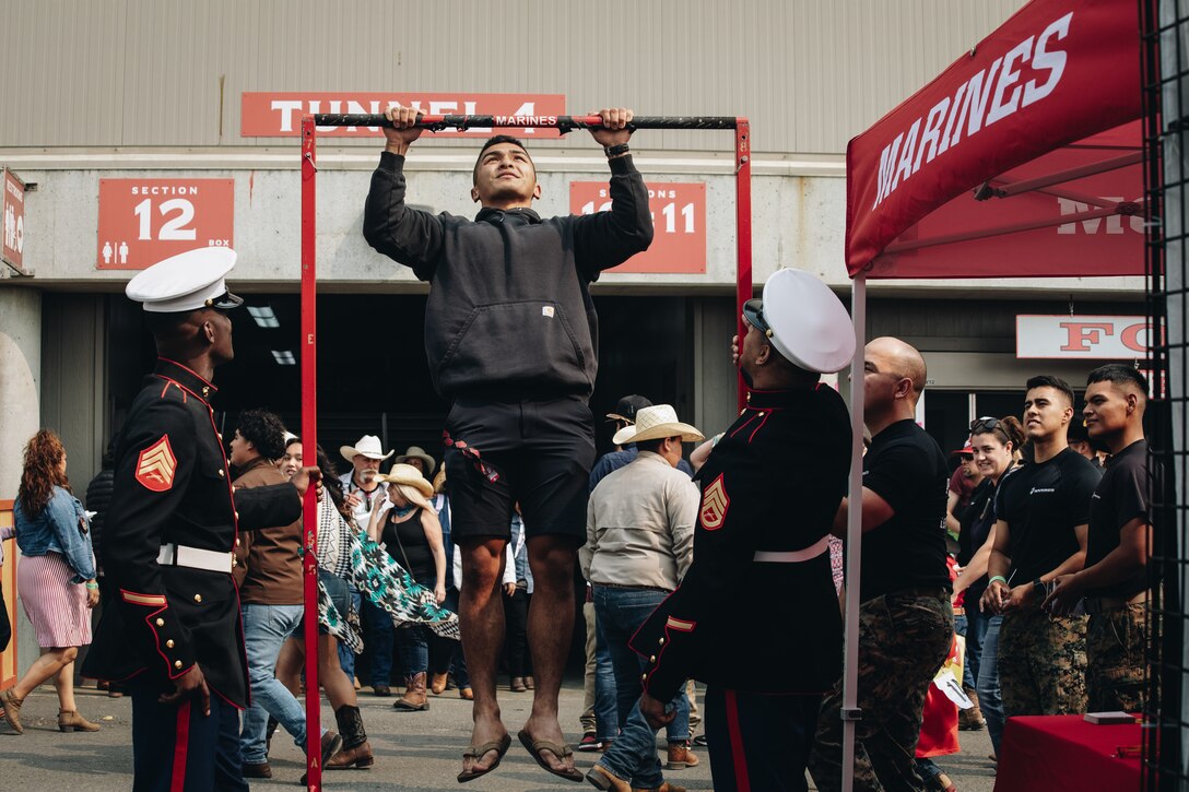 A rodeo attendee attempts pull-ups during a Marine Corps Pull-Up Challenge at the Salinas Rodeo in Salinas, California Sept.  25, 2021. The Marines of Recruiting Sub-Station Salinas hosted a pull-up challenge and talked to rodeo attendees interested in learning more about the opportunities available within the Marine Corps. (U.S. Marine Corps photo by Sgt. Alina Thackray)