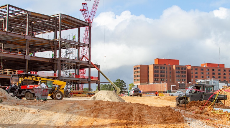 Contractors work on constructing the steel structure forming the main portion of the new hospital on the left, while the current General Leonard Wood Army Community Hospital sits farther back to the right at Fort Leonard Wood, Mo., on Sept. 1, 2021. The current hospital will be demolished after construction is finished, and the area will turn into extra parking for patients and staff.