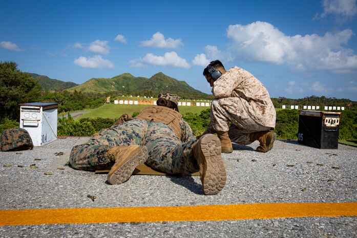 U.S. Marine Corps Sgt. Morelia Capuchino Diaz, a food service specialist with Camp Courtney Mess Hall, Combat Logistics Regiment 37, receives guidance from a Combat Marksmanship Coach during the new Annual Rifle Qualification on Camp Hansen, Okinawa, Japan, Oct. 5, 2021. The ARQ is a three-day, combat-centric course of fire that tests Marines’ marksmanship skills in a dynamic-shooting environment. Shooters utilize artificial support, engage moving targets as well as engage targets while on the move.