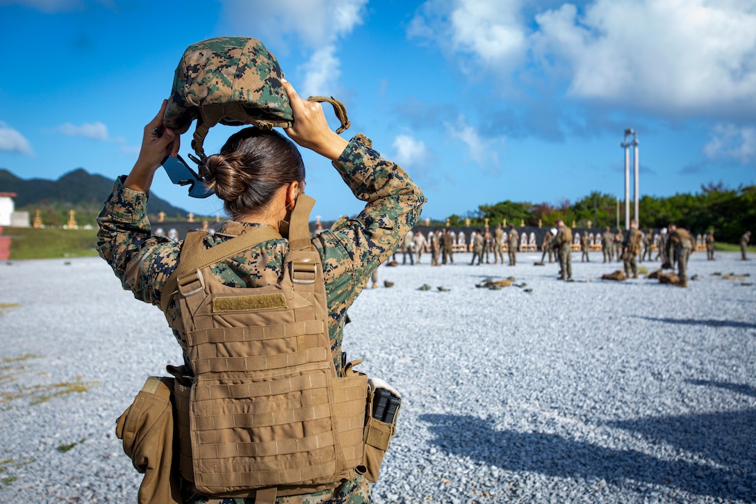 U.S. Marine Corps Sgt. Morelia Capuchino Diaz, a food service specialist with Camp Courtney Mess Hall, Combat Logistics Regiment 37, places on a kevlar as she walks to the firing line during the new Annual Rifle Qualification on Camp Hansen, Okinawa, Japan, Oct. 5, 2021. The ARQ is a three-day, combat-centric course of fire that tests Marines’ marksmanship skills in a dynamic-shooting environment. Shooters utilize artificial support, engage moving targets as well as engage targets while on the move.