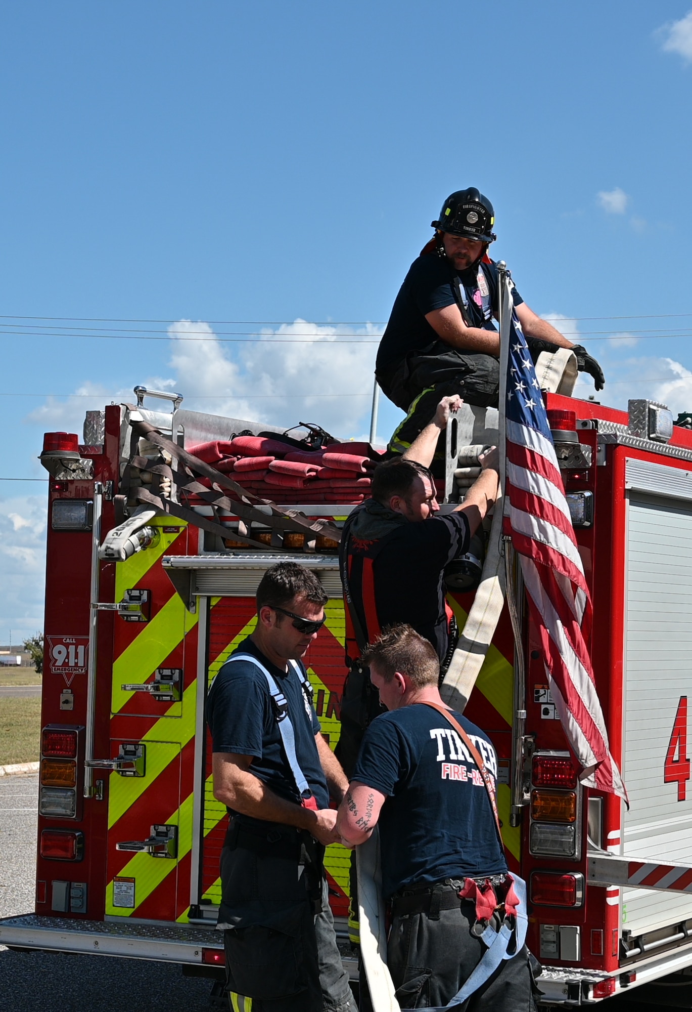 Four firefighters with a fire truck and American flag