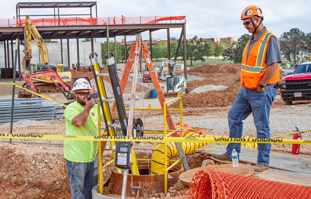 U.S. Army Corps of Engineers, Kansas City District Missouri Resident Office Hospital Low Voltage Quality Assurance Officer Ryan Snyder (right) works alongside the contracted low voltage quality control officer as he lowers wire underground on-site of the new hospital at Fort Leonard Wood, Mo., on Sept. 1, 2021.