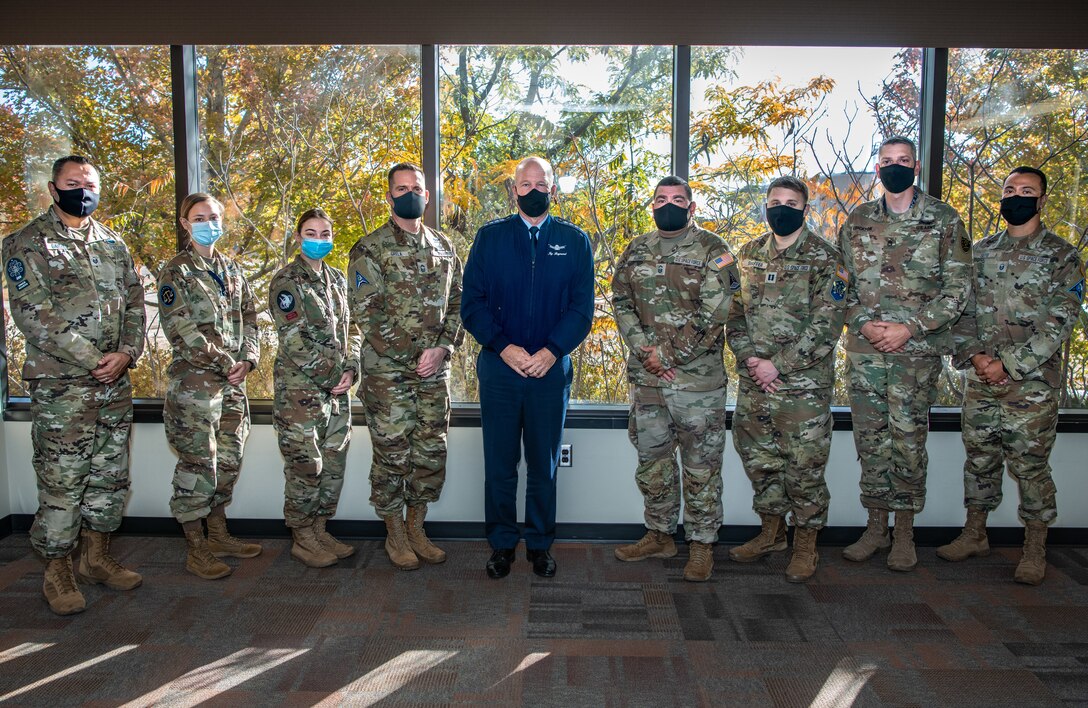 General Raymond poses with guardians in front of a window at the dining facility on schriever space force base.