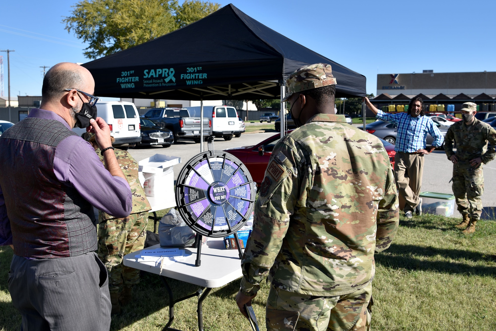 (left) Jimm Harper, 301st Fighter Wing violence prevention integrator, talks with Staff Sgt. Bruner Lafayette, 73rd Aerial Port Squadron load planner, during a Domestic Violence Awareness event, October 16, 2021, at U.S. Naval Air Station Joint Reserve Base Fort Worth, Texas. Guests spun the wheel for prompted hypothetical situations to discuss approaches to potential domestic violence. (U.S. Air Force photo by Staff Sgt. Randall Moose)