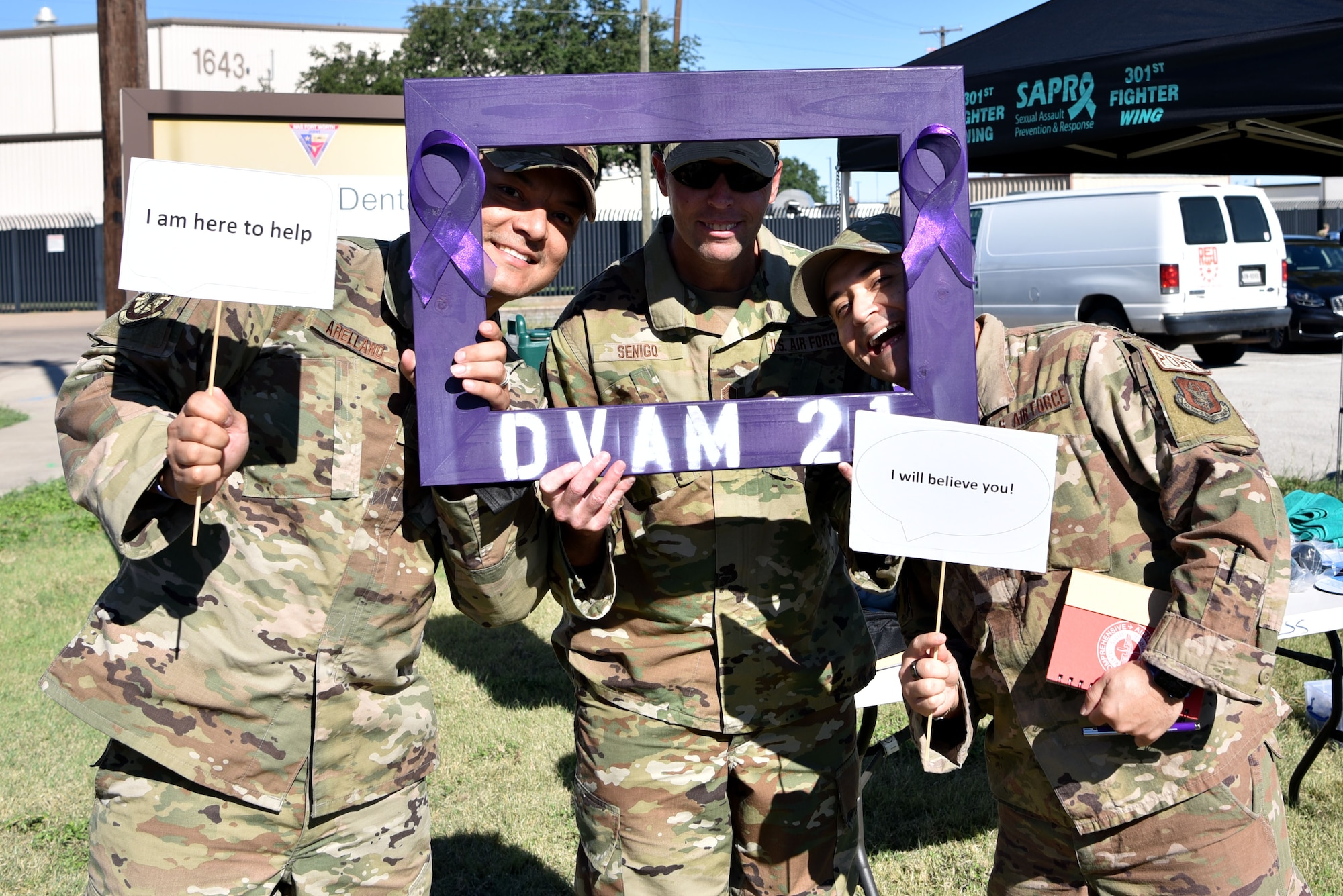 (left) Tech. Sgt. Ruben Arellano, 73rd Aerial Port Squadron tractor supervisor, (center) Chief Master Sgt. Michael Senigo 301st Fighter Wing command chief, and Tech. Sgt. Cesar Martinez, 73d APS cargo processing supervisor, display support messages during a Domestic Violence Awareness event, October 16, 2021, at U.S. Naval Air Station Joint Reserve Base Fort Worth, Texas. 301 FW Airman & Family Readiness Center hosted the event to provide domestic violence prevention information as well as creating culture of connectedness. (U.S. Air Force photo by Staff Sgt. Randall Moose)