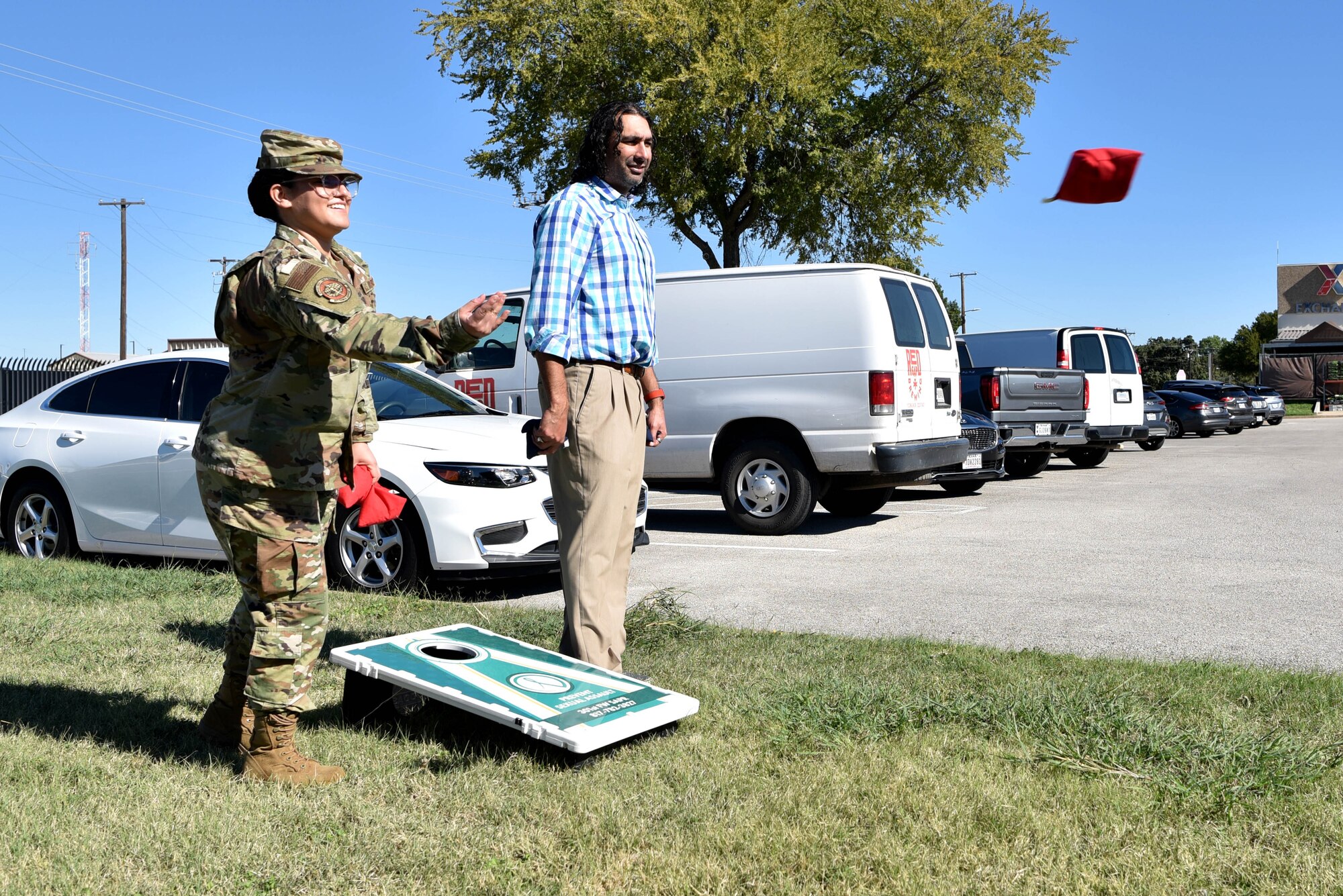 Staff Sgt. Dalilah Jimenez, 301st Fighter Wing Airman & Family Readiness Center supervisor, and Mr. Scott Palomino, A&FRC director, toss beanbags during a Domestic Violence Awareness event, October 16, 2021, at U.S. Naval Air Station Joint Reserve Base Fort Worth, Texas. The A&FR Center set up tables with free coffee, doughnuts, and a bean bag toss game to encourage comradery and conversation during a lunchbreak. (U.S. Air Force photo by Staff Sgt. Randall Moose)