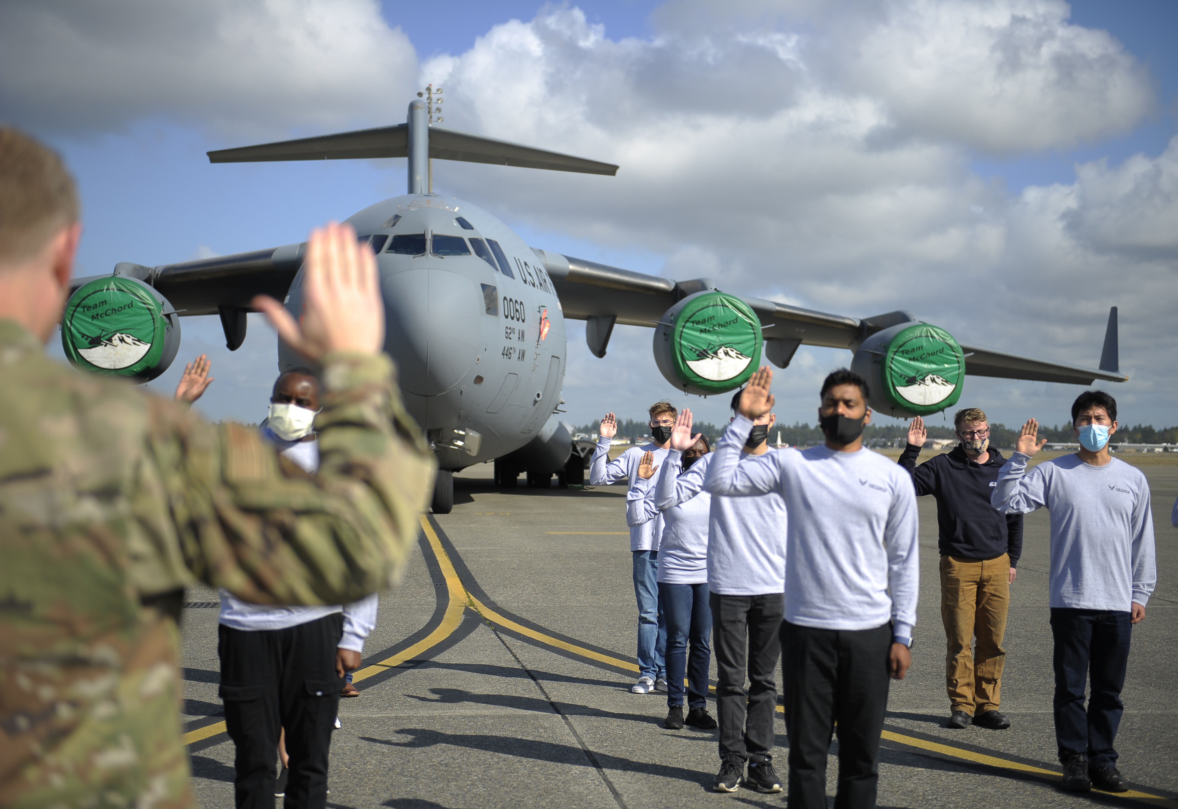 Airman raises his right hand and administers Oath of Enlistment to recruit in front of an aircraft.