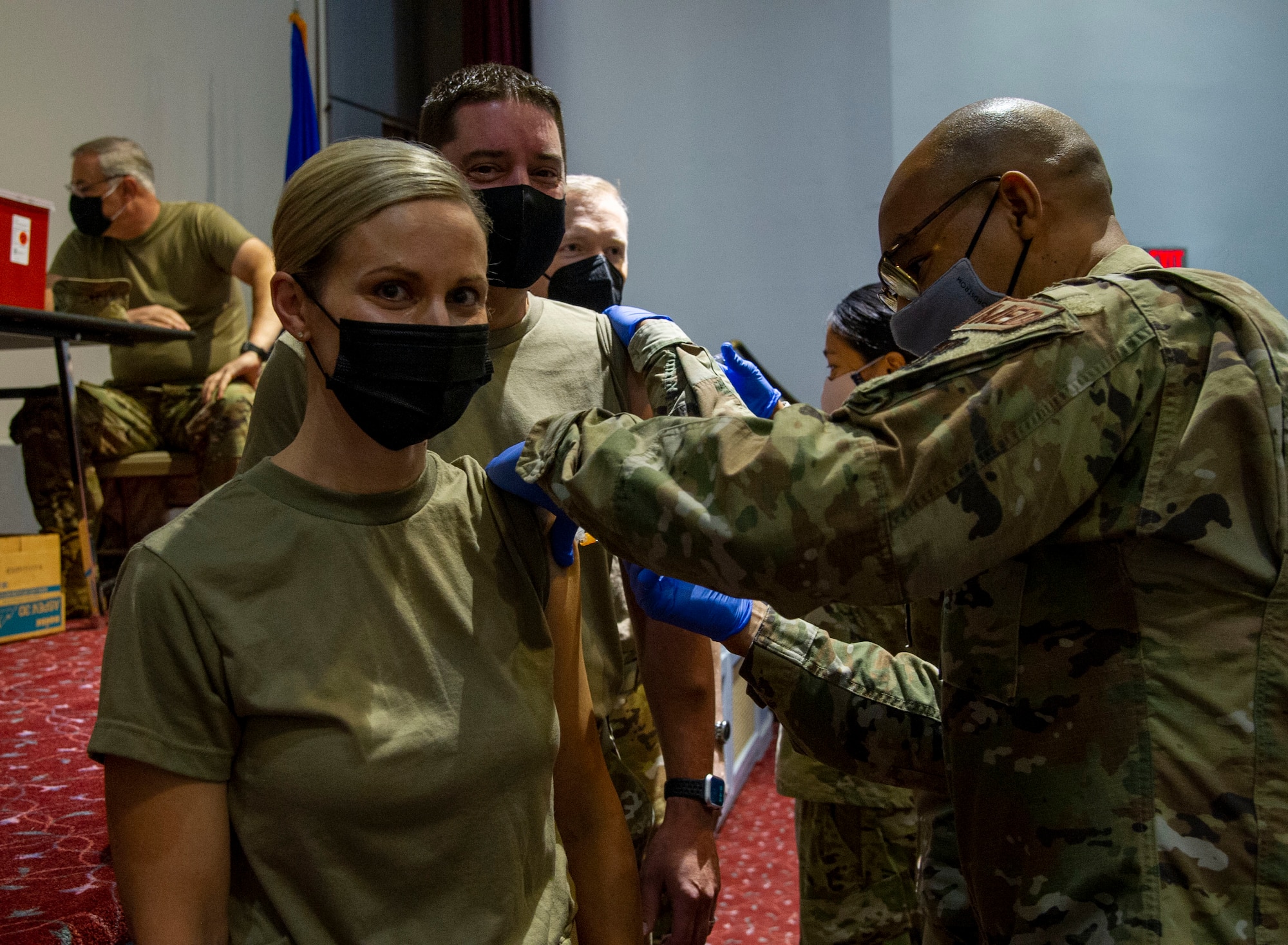 Three Air Force leaders receive flu shots from medical technicians.