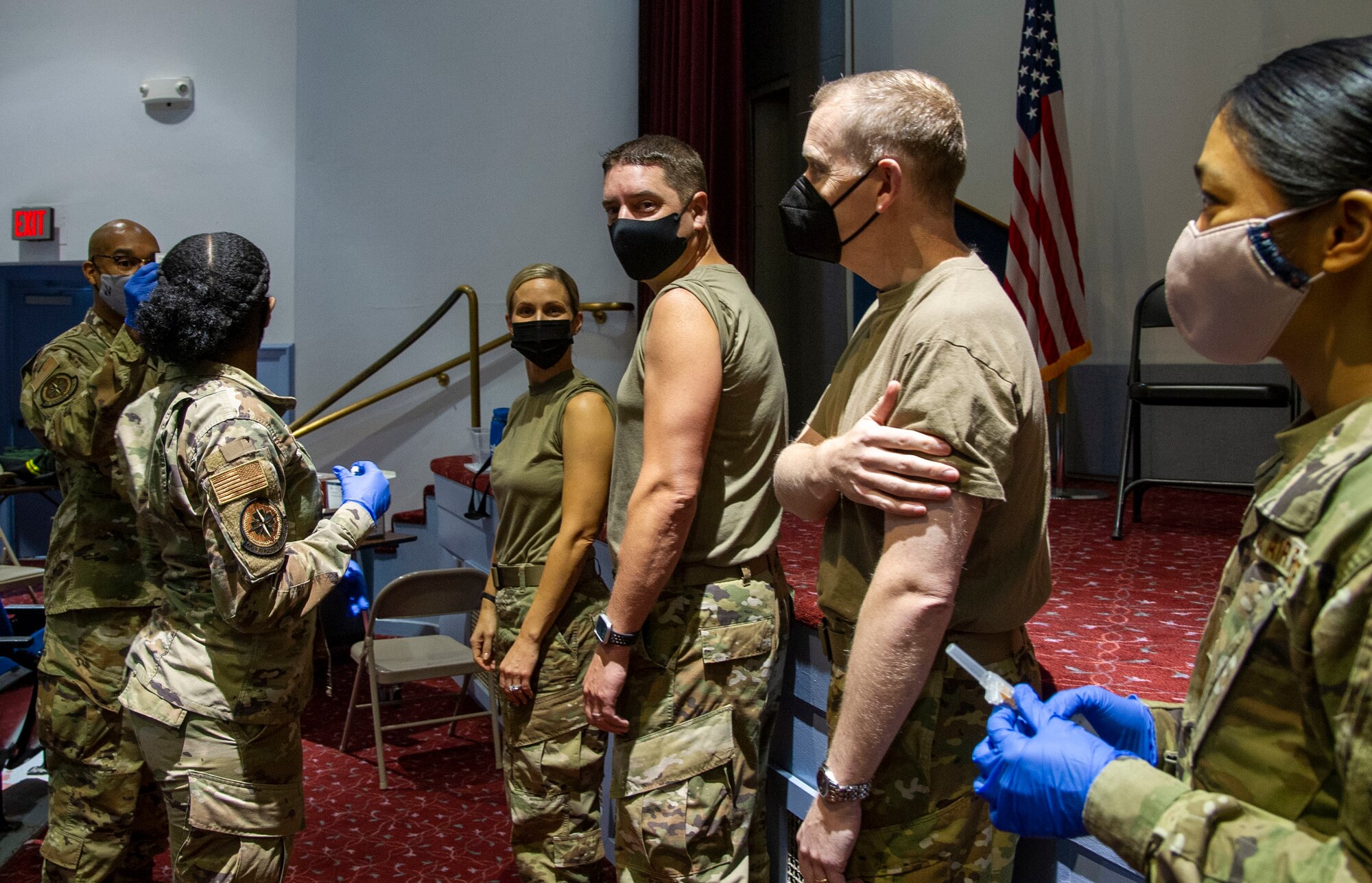 Airmen roll up sleeves before medical technicians.