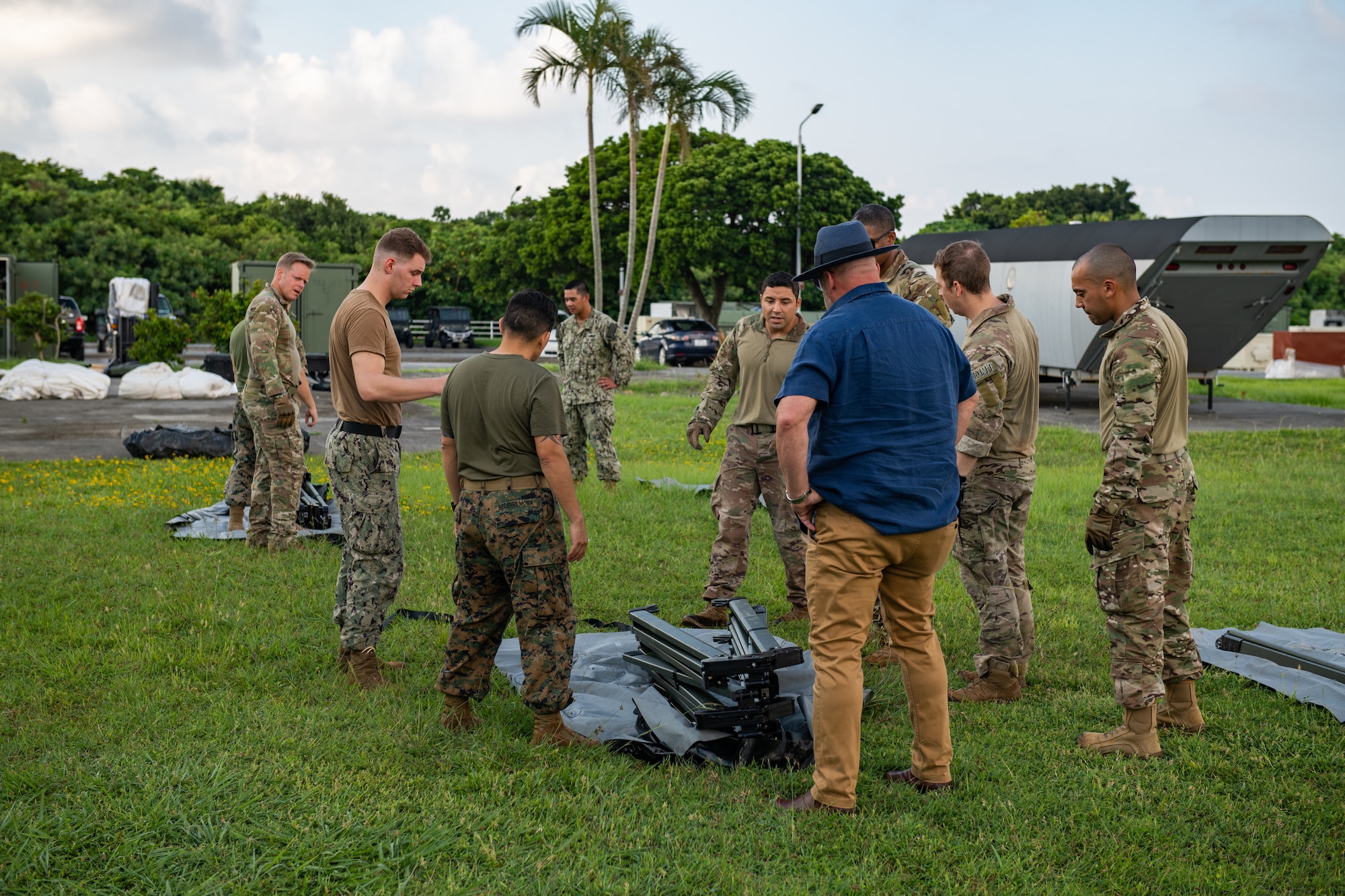 Military members gather around an unopened tarp that will become a big medical tent