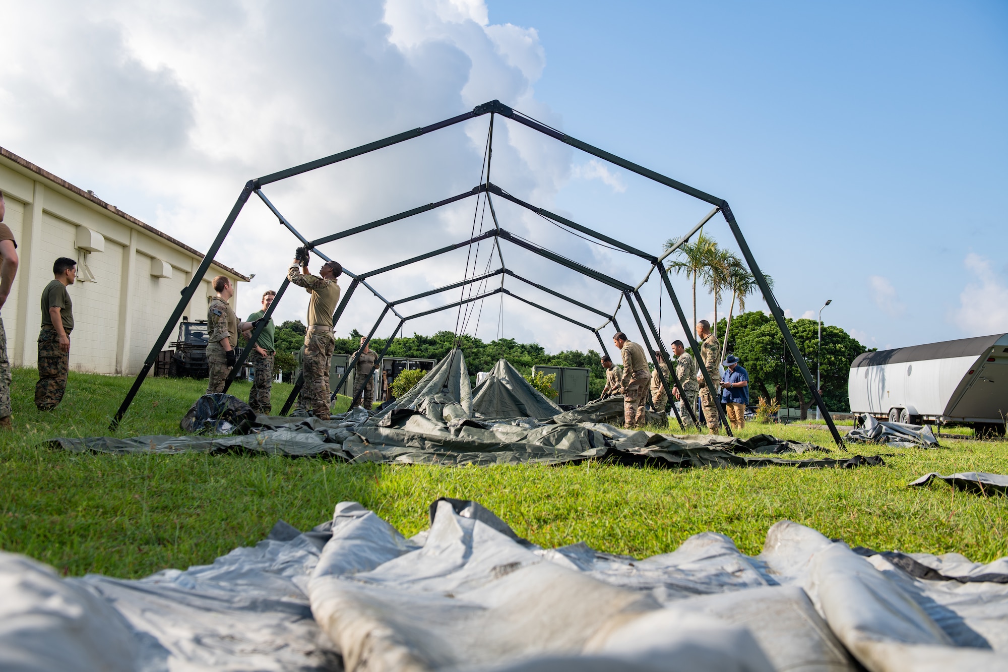 The frame of a tent is worked on by multiple military personnel