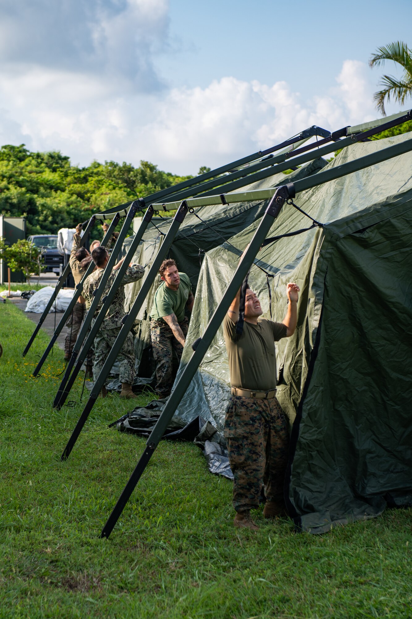 4 Military personnel tighten flaps to the frame of a big tent