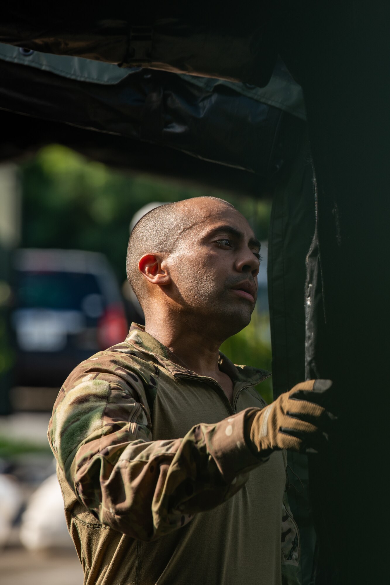 A man wearing gloves observes the flap near the entrance of a tent