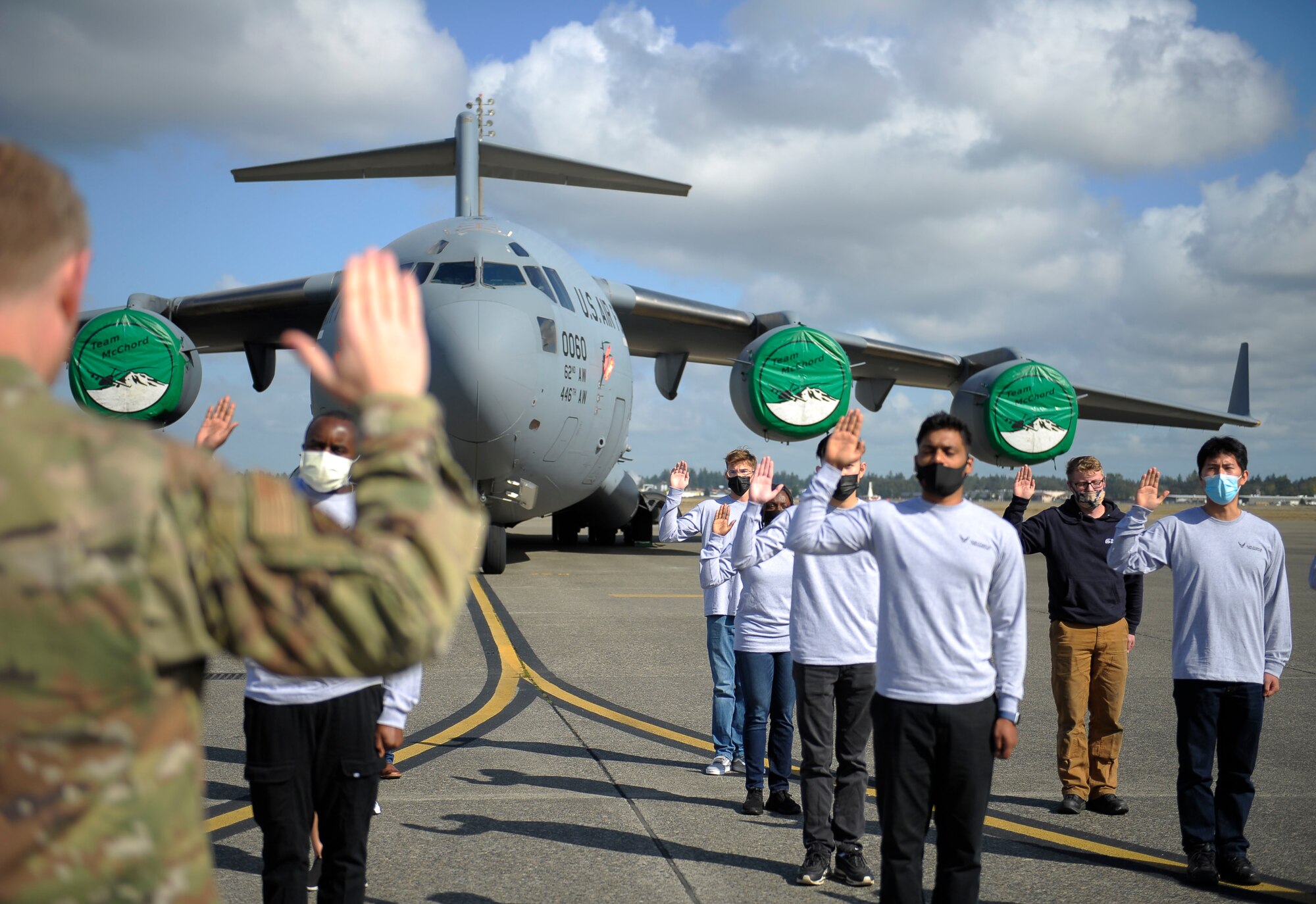 Airman raises his right hand and administers Oath of Enlistment to recruit in front of an aircraft.