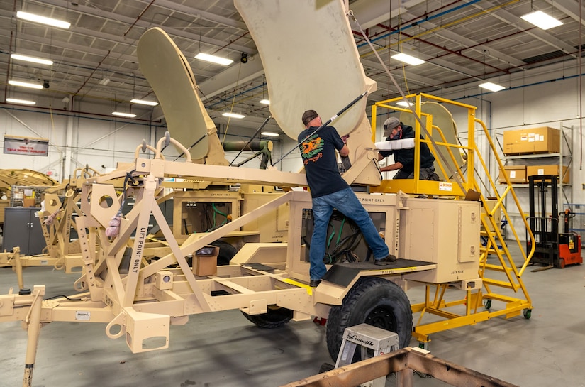 Photo of Joe Polny, left, and Jeff Urbanovage replacing a lift cable on an AN/TSC-167 Satellite Transportable Terminal (STT)