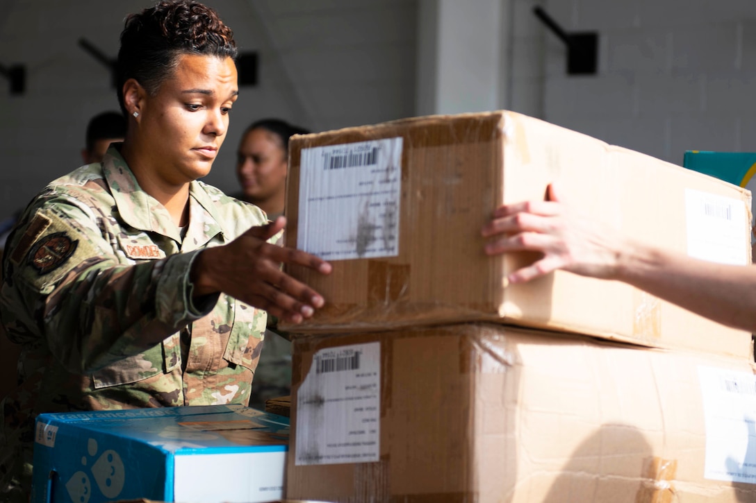 A service member handles cardboard boxes.