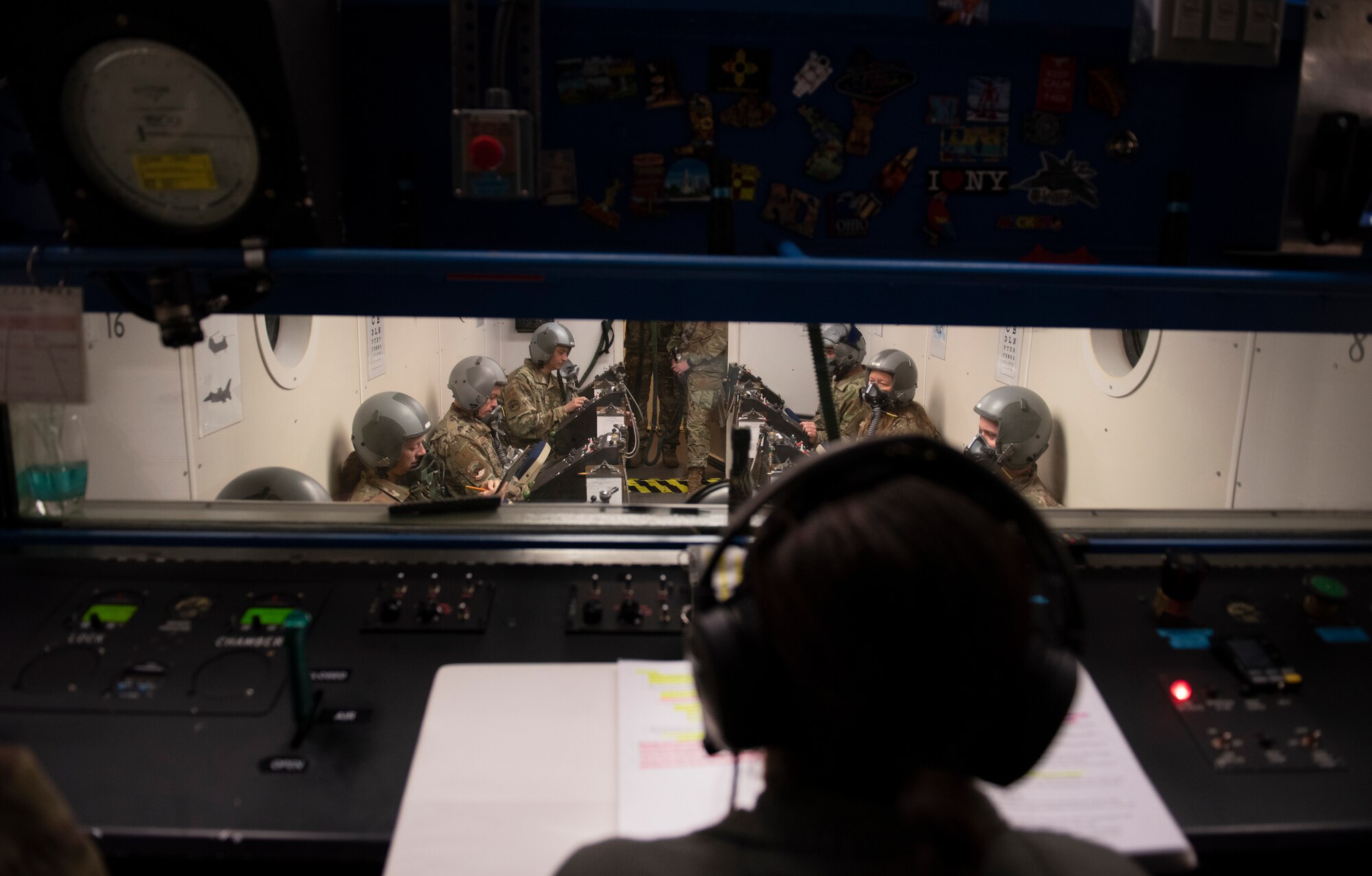 an airman sits in front of the hypobaric chamber talking to students as they experience hypoxia