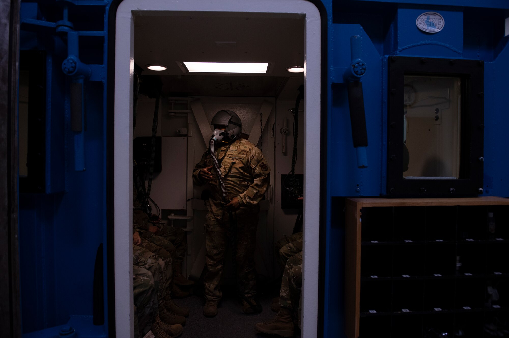 an airman stands in the hypobaric chamber instructing students on how to react to a rapid decompression