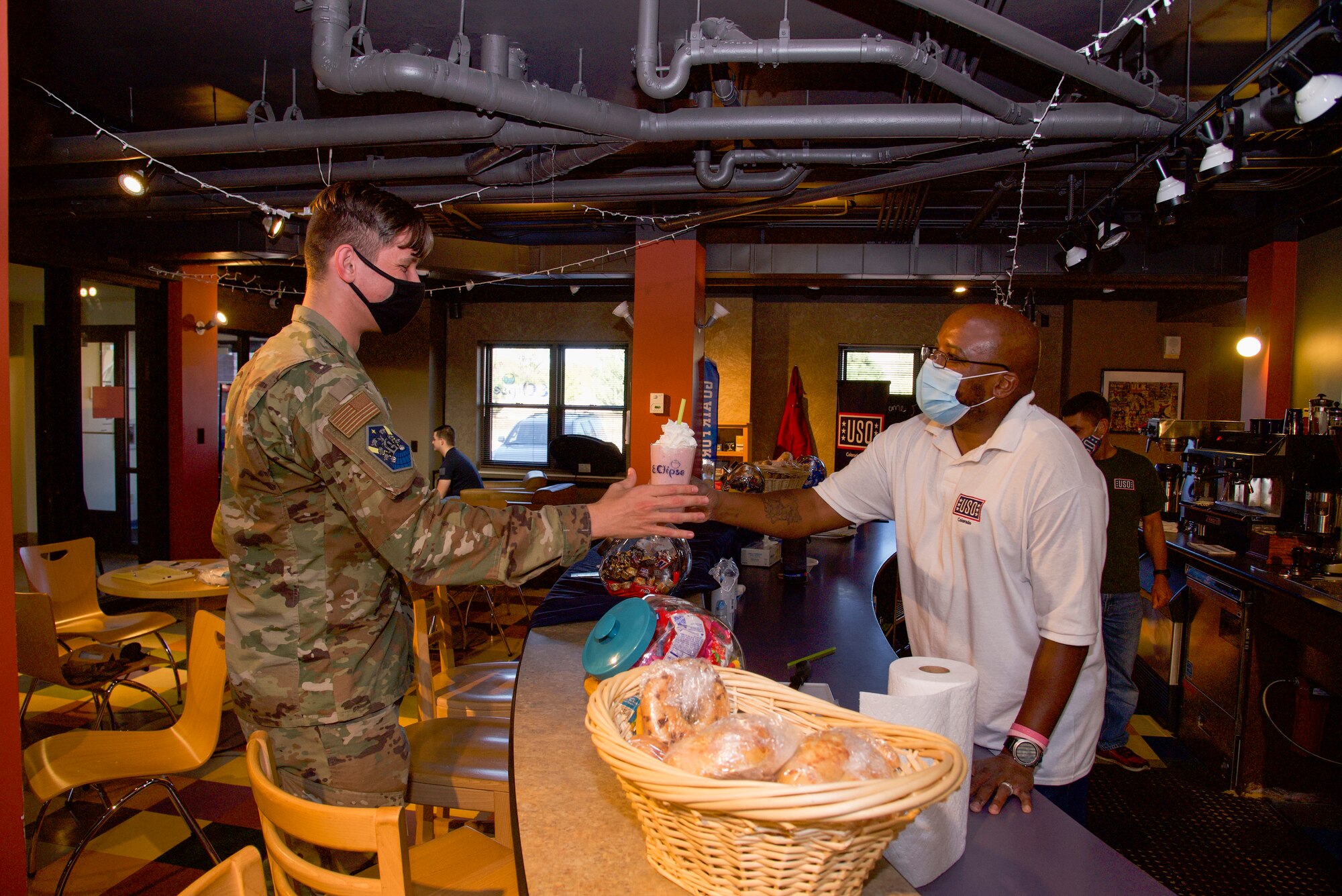 United Service Organizations employee Corey Wood hands U.S. Air Force Airman 1st Class Ryan Prince, Peterson-Schriever Garrison Public Affairs mass communication specialist, a freshly made smoothie at the Eclipse Café on Peterson Space Force Base, Colorado, Oct. 5, 2021.