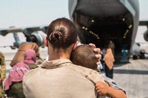 U.S. Marine Corps Cpl. Caitlin McCormick, an Evacuation Control Center Marine, carries a child to a plane at Al Udeid Air Base, Qatar, Sept. 1, 2021. The Department of Defense is committed to supporting the evacuation of American citizens, Special Immigrant Visa applicants and other at-risk individuals from Afghanistan. (U.S. Marine Corps photo by Lance Cpl. Kyle Jia)