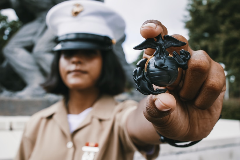 A Marine holds up a pin that represents the Marine Corps.