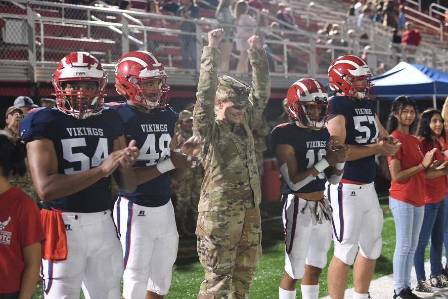 U.S Air Force Col. Jocelyn Schermerhorn, commander of the 1st Special Operations Wing, Hurlburt Field, Florida, cheers with varsity football players at the 2021 Military Appreciation football game on October 7th, 2021. She was invited to perform the opening coin toss for the game between the Fort Walton Vikings and the Escambia Gators. (U.S. Air Force photo by Staff Sgt. Tarelle Walker)
