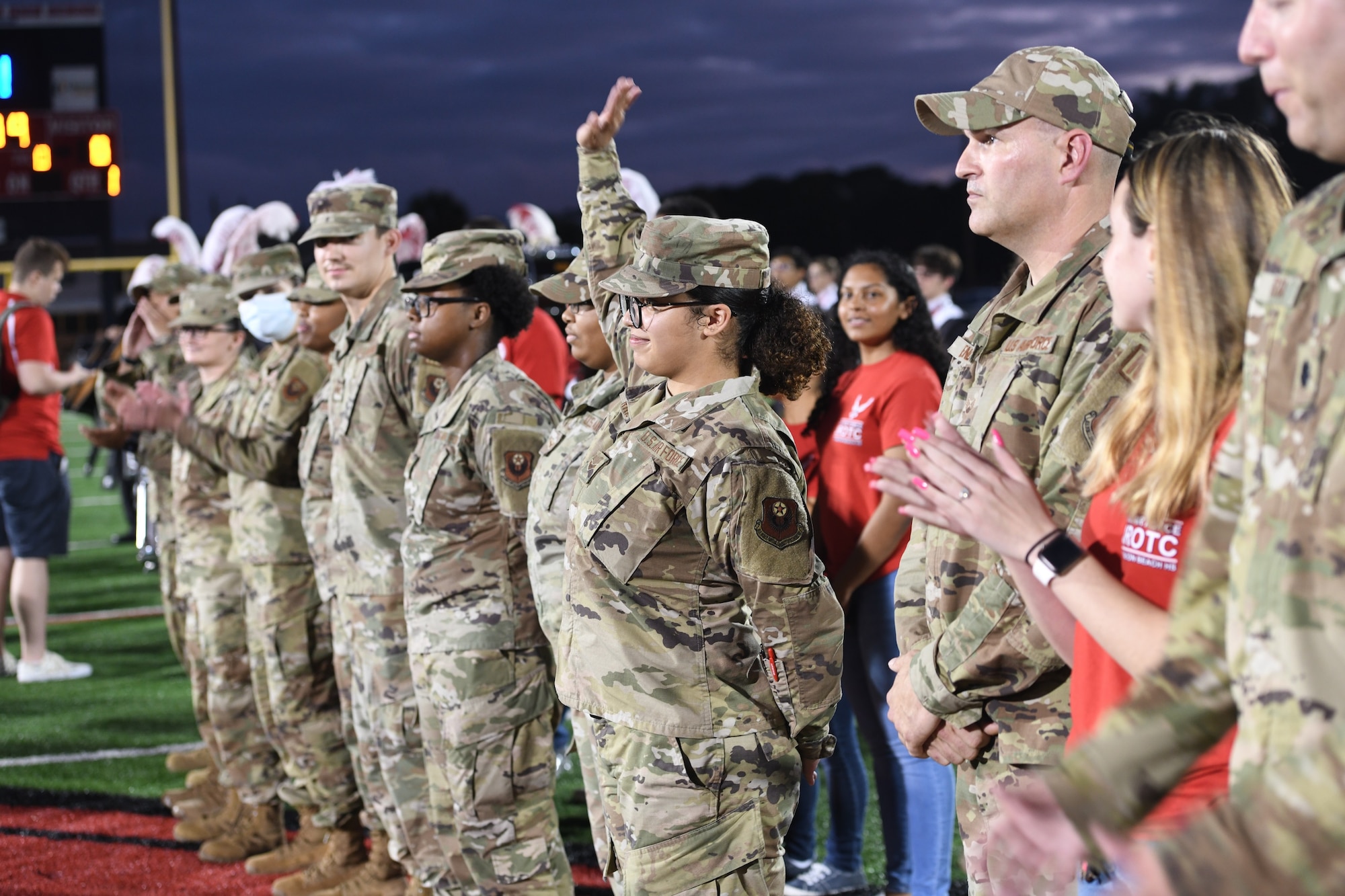 U.S Air Force Airmen 1st Class, Shayla Harris, part of the 1st Special Operations Wing Medical Group Health Service Management team, raises her hand at centerfield during the Fort Walton Beach high school Military Appreciation football game.  Airman 1st Class Harris was one of nine Airmen highlighted for their efforts in helping with COVID-19 mitigation for service members at Hurlburt Field. (U.S. Air Force photo by Staff Sgt. Tarelle Walker)