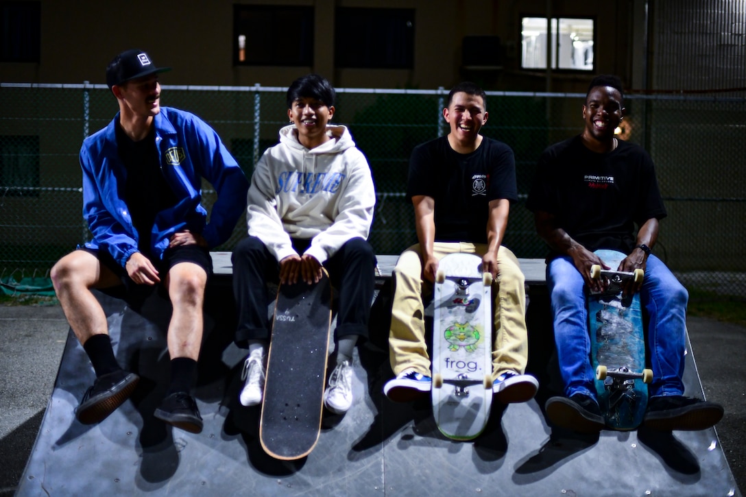 Service members sit on a skate ramp.