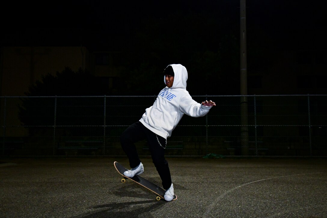 An Airman does a trick on his skateboard.