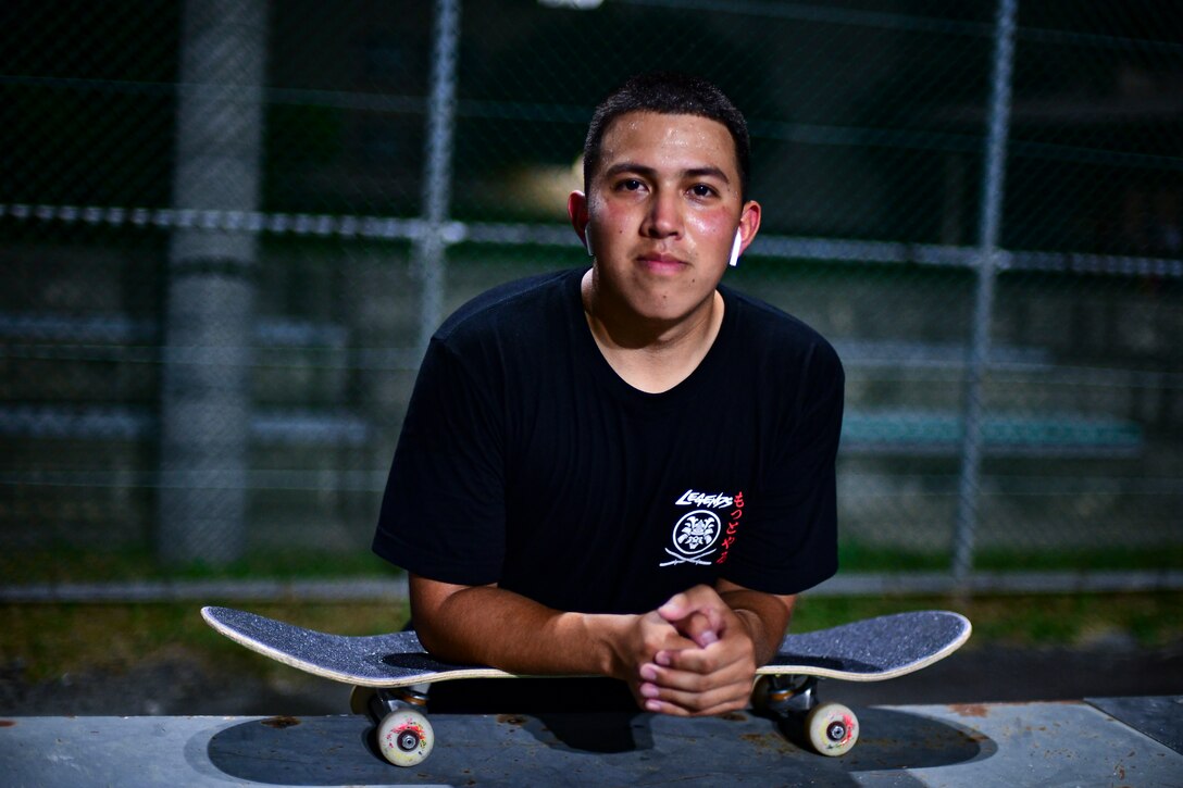A soldier leans on his skateboard.