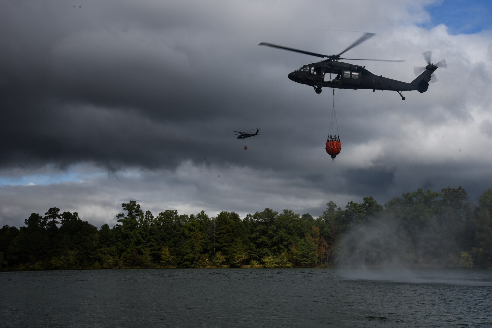 Virginia Army National Guard flight crews conduct water bucket training with UH-60 Black Hawk helicopters Oct. 12, 2021, at a training area in Chesterfield, Virginia. Aviation assets can support fire-fighting efforts with the use of water buckets, which require periodic training for flight crews in order to ensure equipment proficiency. These Soldiers are scheduled to deploy to Kosovo with the Sandston-based 2nd Battalion, 224th Aviation Regiment, 29th Infantry Division in early 2022, where fire-fighting capabilities may be needed. (U.S. Army National Guard photo by Sgt. 1st Class Terra C. Gatti)
