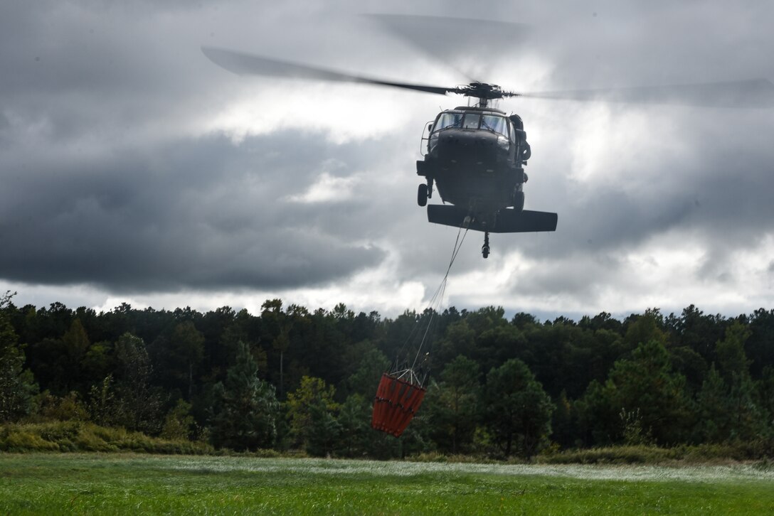 Virginia Army National Guard flight crews conduct water bucket training with UH-60 Black Hawk helicopters Oct. 12, 2021, at a training area in Chesterfield, Virginia. Aviation assets can support fire-fighting efforts with the use of water buckets, which require periodic training for flight crews in order to ensure equipment proficiency. These Soldiers are scheduled to deploy to Kosovo with the Sandston-based 2nd Battalion, 224th Aviation Regiment, 29th Infantry Division in early 2022, where fire-fighting capabilities may be needed. (U.S. Army National Guard photo by Sgt. 1st Class Terra C. Gatti)