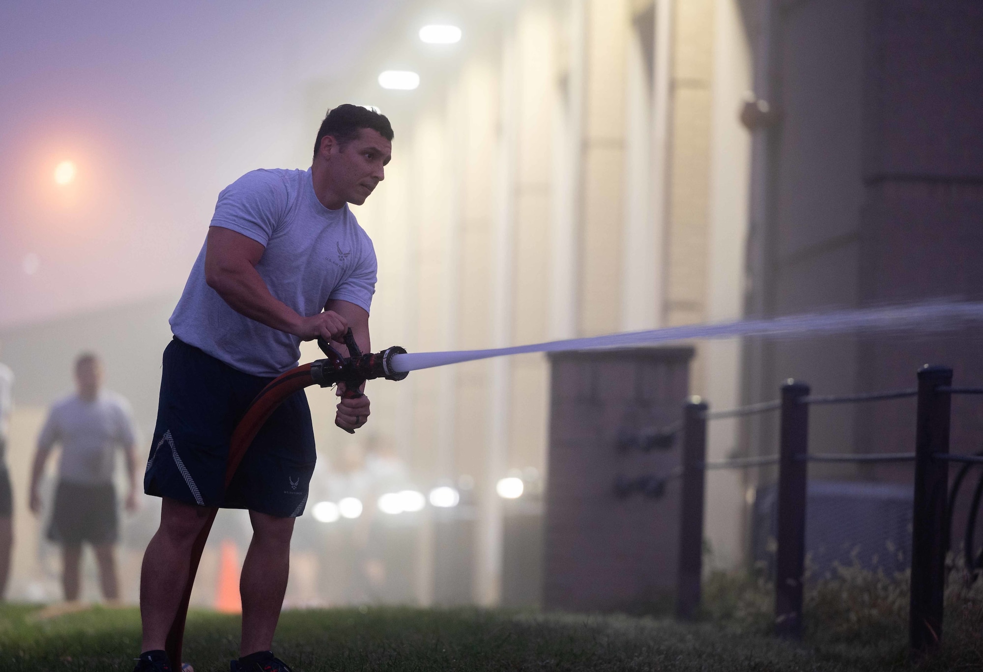 Staff Sgt. Jaheel Morales, 436th Civil Engineer Squadron engineering journeyman, sprays a firehose during a physical training session at the firehouse on Dover Air Force Base, Delaware, Oct. 14, 2021. The Dover AFB fire department hosted a firefighter centric workout for squadron members that featured farmer carries, hose drags and ladder climbs, as part of Fire Prevention Week 2021. (U.S. Air Force photo by Senior Airman Faith Schaefer)