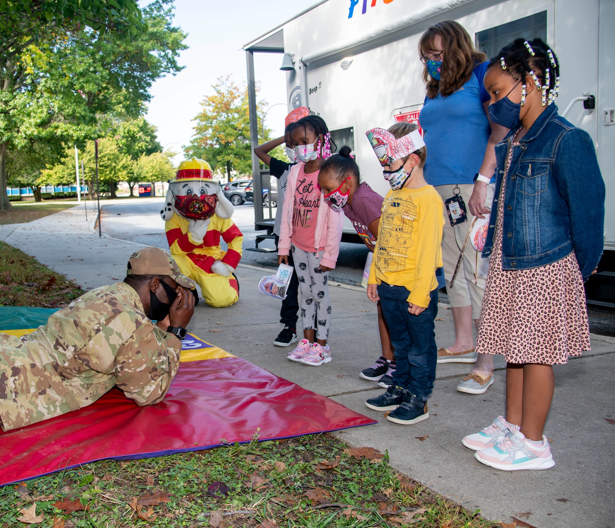 Staff Sgt. Marcus Scriven, 436th Civil Engineer Squadron firefighter, teaches students from Major George S. Welch Elementary School how to stop, drop and roll and other fire safety tips during a visit for Fire Prevention Week on Dover Air Force Base, Delaware, Oct. 15, 2021. Fire Prevention Week is an annual observance to educate the Dover AFB community about the importance of fire prevention. (U.S. Air Force photo by Tech. Sgt. Nicole Leidholm)