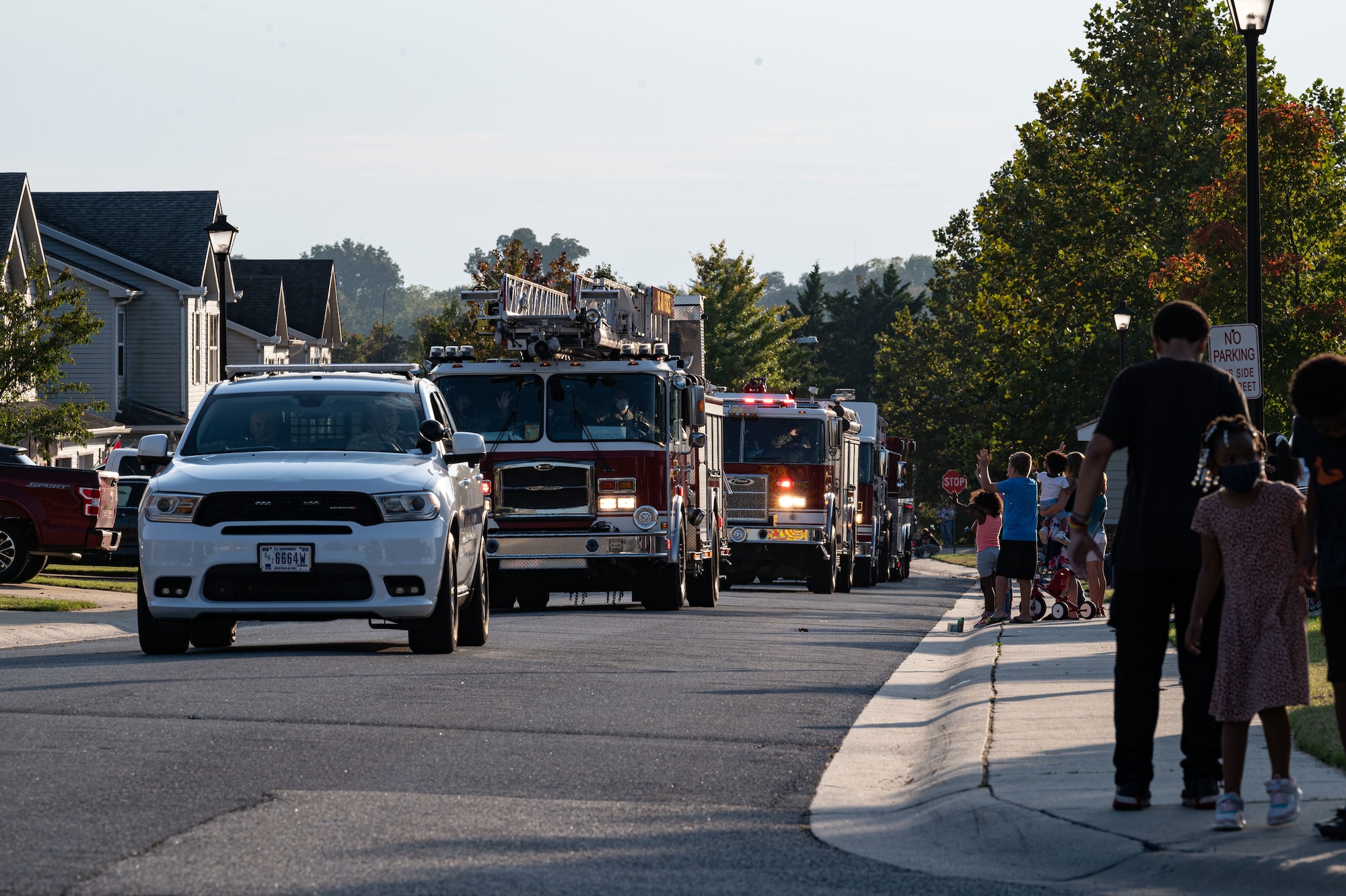 Base housing residents wave at emergency response vehicles during the 2021 Fire Prevention Week Parade on Dover Air Force Base, Delaware, Oct. 15, 2021. This year’s Fire Prevention Week campaign, themed “Learn the Sounds of Safety,” educated everyone about the different sounds smoke and carbon monoxide alarms make. (U.S. Air Force photo by Senior Airman Marco A. Gomez)