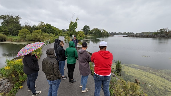 People standing on a concrete walkway next to a wetland pond.