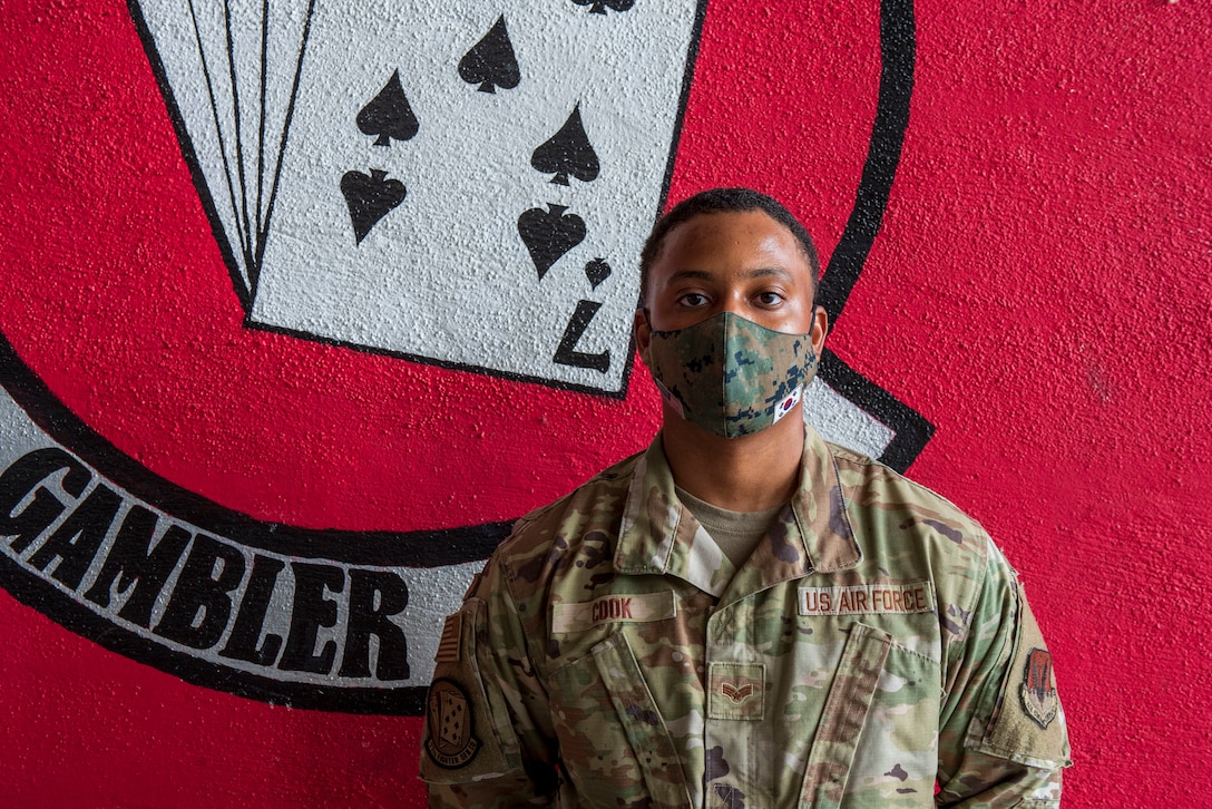 Photo of Airman in front of unit logo.