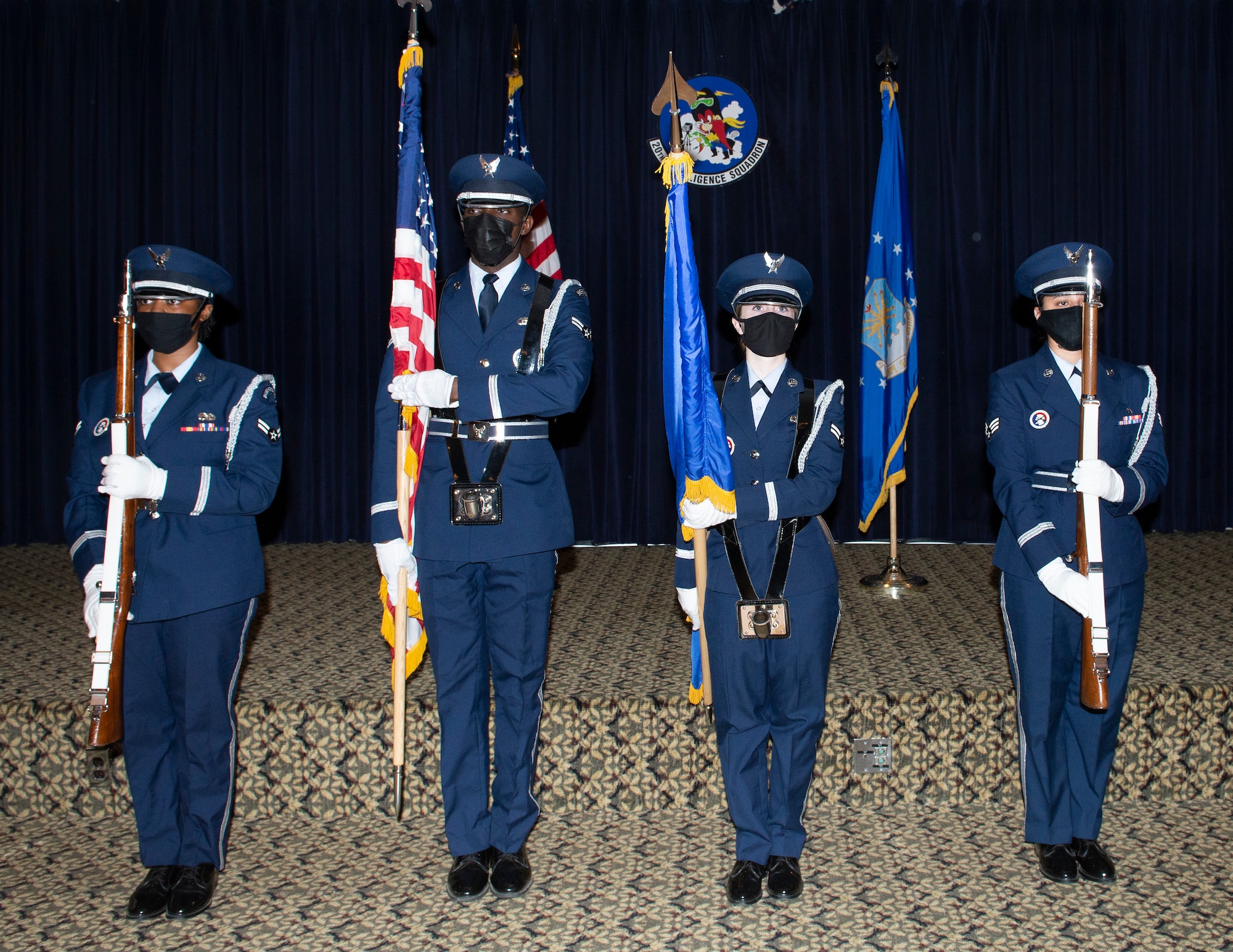 Four-person Air Force honor guard presenting the colors with two flags and two rifles.