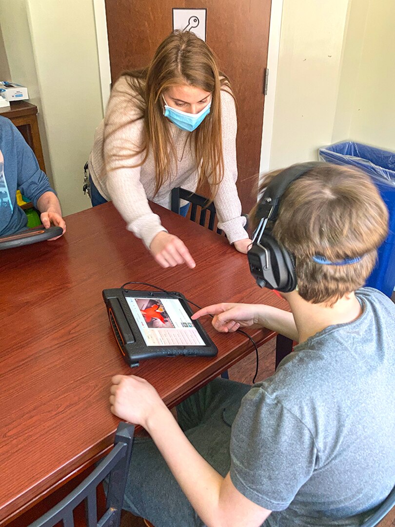 A teacher assists a student using a touchscreen device.