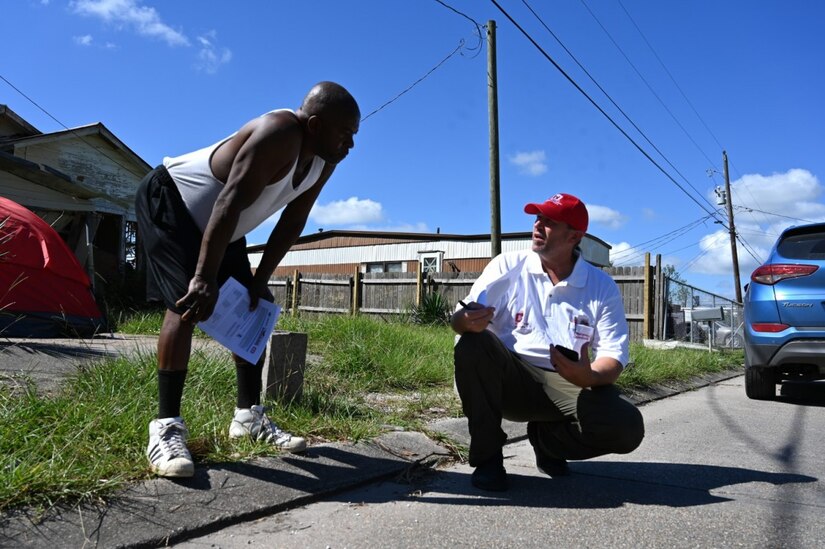 Two men speak on a street.