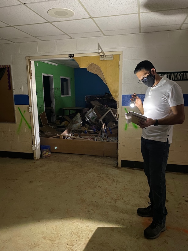 Electrical Engineer Sam Jaser uses his flashlight to review schematics of Waverly Elementary School