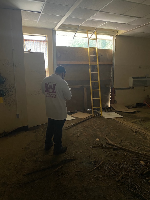 Cost Engineer Omar Acevedo surveys empty room for estimated repair costs.