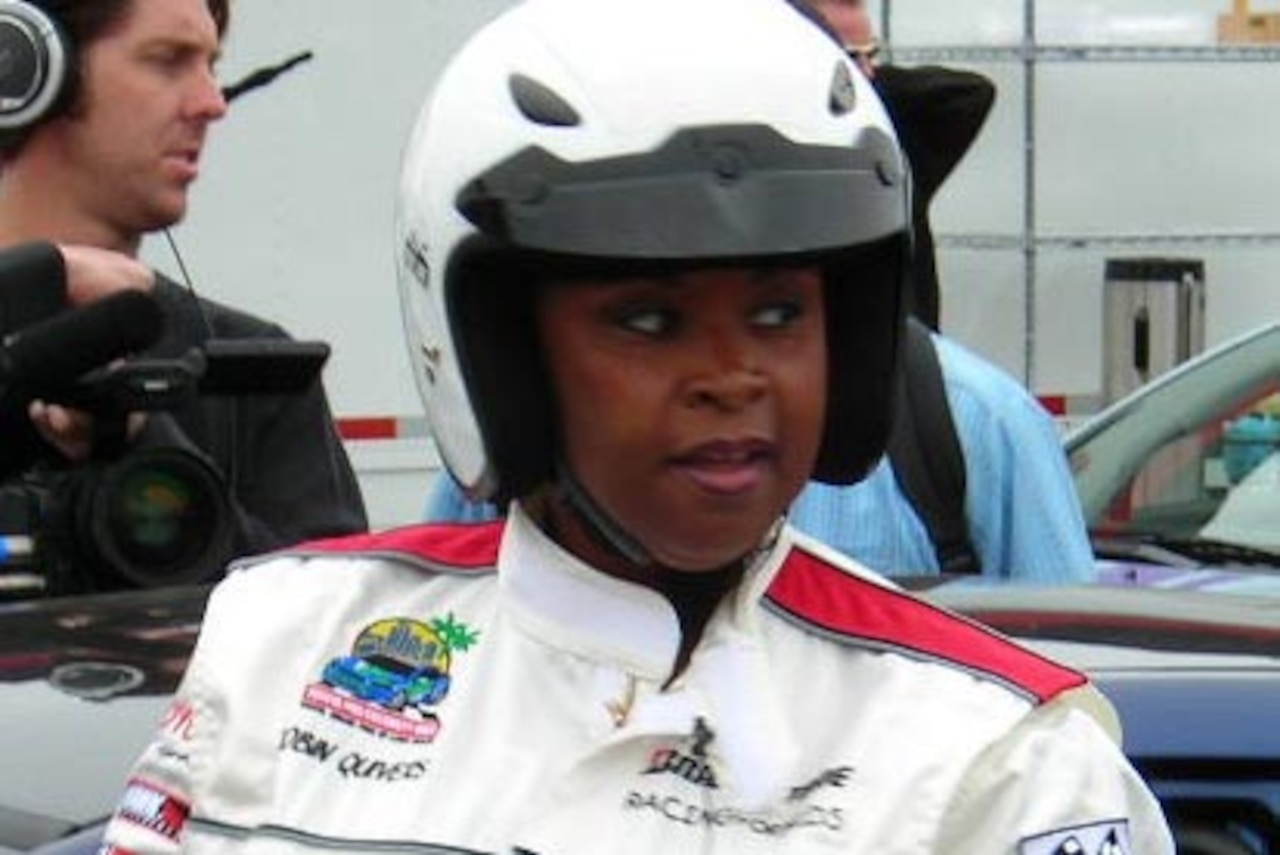 A race car driver looks at something to her left.