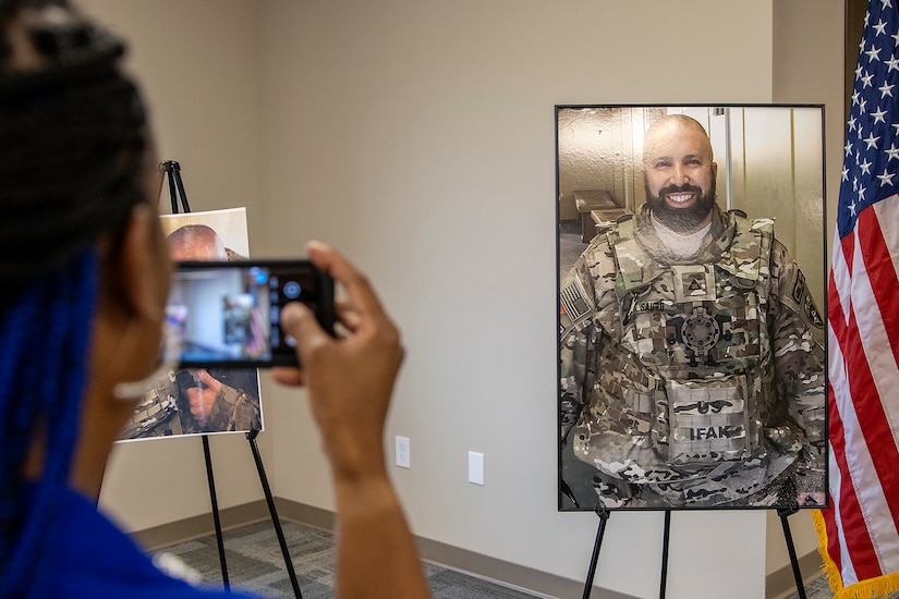 Jamicka Edwards takes a photo of an image of Michael G. Sauro, a former Defense Ammunition Center hazardous material instructor who lost his life while deployed as a civilian in support of Operation Freedom’s Sentinel, during a building dedication ceremony at Camp Atterbury, Ind., June 3, 2021. Edwards, who went to high school with Sauro, was invited along with his family and family friends to witness Building 444 be named the Michael G. Sauro Mobilization and Training Facility. (U.S. Army photo by Mark R. W Orders-Woempner)