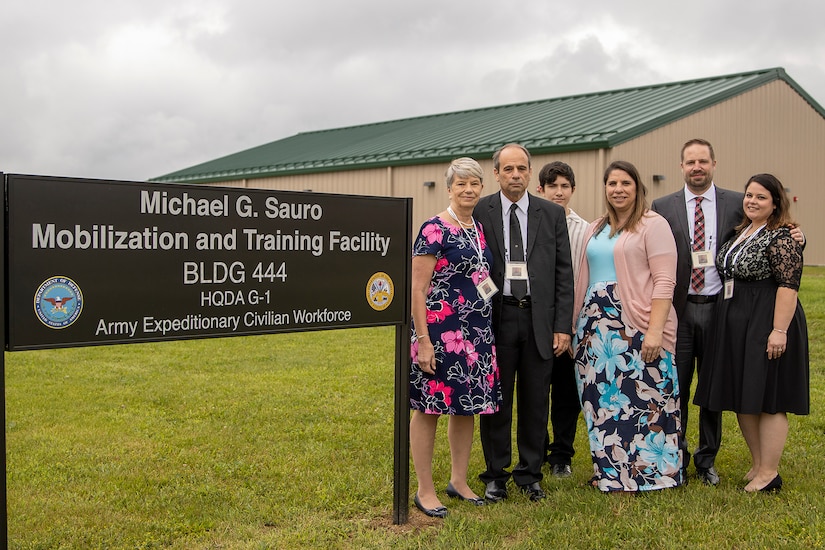 The family of Michael G. Sauro, a former Defense Ammunition Center hazardous material instructor who lost his life while deployed as a civilian in support of Operation Freedom’s Sentinel, pose for a photo in front of a facility named in Sauro’s honor at Camp Atterbury, Ind., June 3, 2021. Pictured from left to right are Christine and Michael E. Sauro, mother and father; William and Brienne Matthews, nephew and sister; and Ben and Sarah Sauro, brother and sister-in-law. (U.S. Army photo by Mark R. W Orders-Woempner)