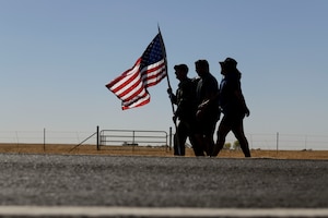 Master Sgt. Scott Downing, 9th Security Forces Squadron (SFS) plans and programs section chief, holds the U.S. flag while rucking with Staff Sgt. Cindy Escobar Johnson, 9th SFS electronics security systems non-commissioned officer, right, and Mike Seymour, 9th SFS anti-terrorism program manager, Oct. 14, 2021, at Beale Air Force Base, California.