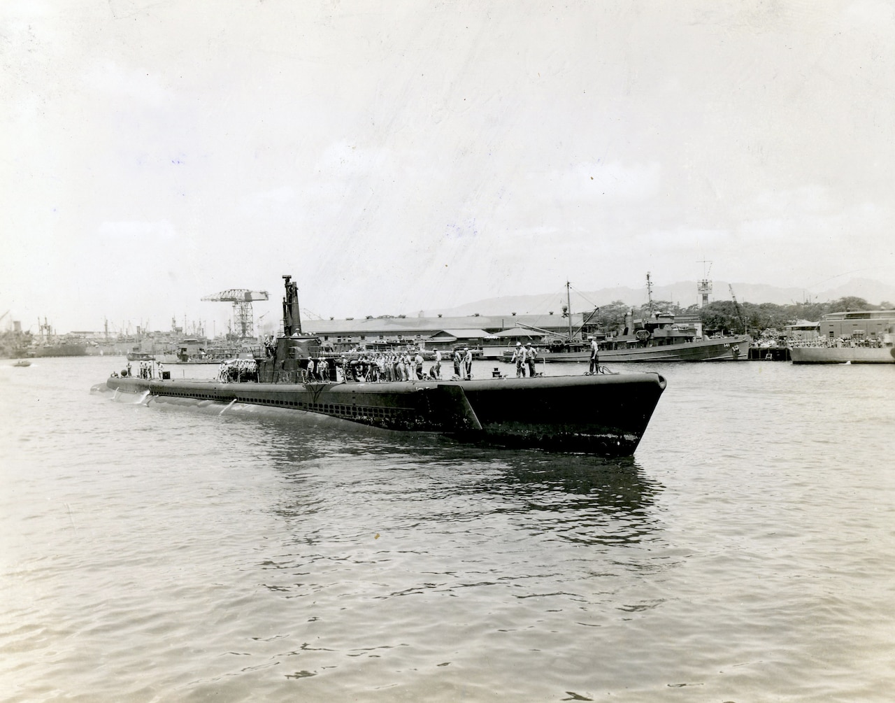 A World War II-era submarine surfaces near a port.