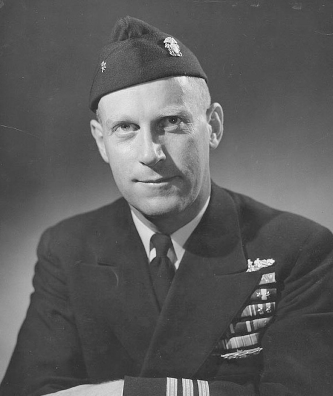 A man in dress uniform and cap poses for a photo.